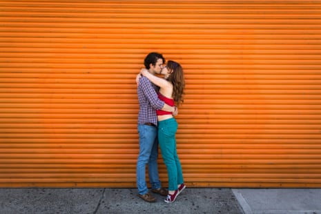 Couple kissing in front of orange shutter