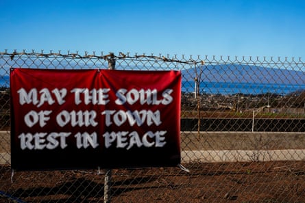 A sign attached to a fence reads ‘May the souls of our town rest in peace’
