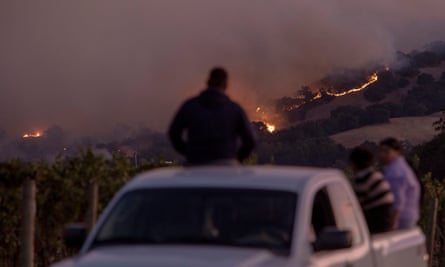 Vineyard workers watch the Kincade fire burning in the hills above Geyserville, California, 24 October 2019.