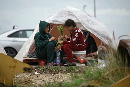 Children arrange a bouquet of flowers outside a small tent