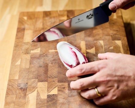 Ben Lippett about to cut a purple chicory with a knife on a wooden block