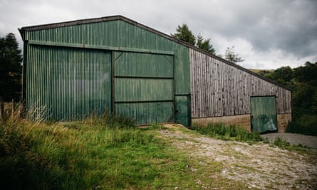 حظيرة في العقار والتي قد تصبح مركزًا تعليميًا - مبنى من الحديد المموج مطلي باللون الأخضر يمكن رؤيته مقابل السماء الرمادية