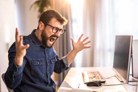 Angry young businessman screaming while working at his home office.