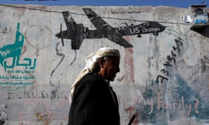A Yemeni man walks past graffiti depicting a US drone.