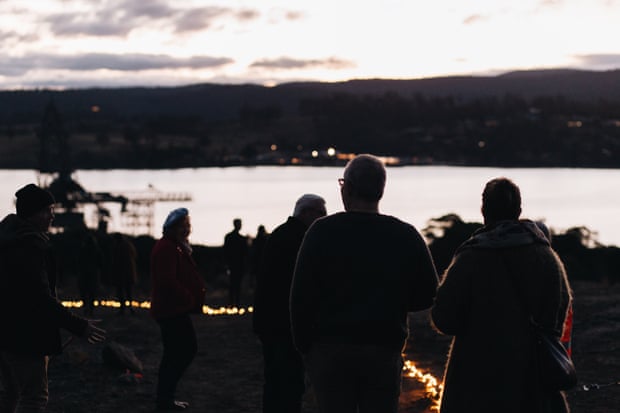 Silhouettes of people and small orange lights on the ground
