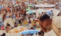 A man puts water on his face on a packed Ipanema beach