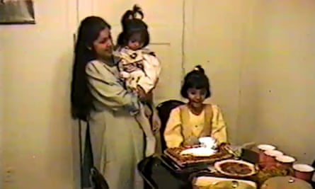 Deux enfants, un dans les bras d'une femme et un assis à une table