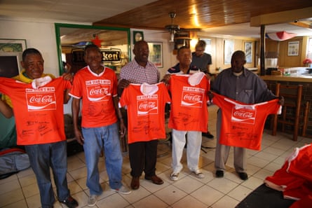 Five of Sir Stan’s Men hold up matching orange football shirts with signatures