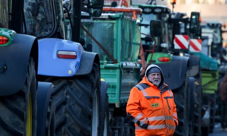 Berlin'de ülke çapındaki çiftçi grevi sırasında bir çiftçi traktörlerin yanında duruyor