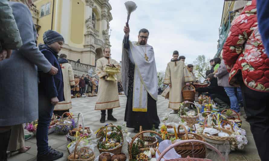 A Ukrainian priest blesses believers as they collect traditional cakes and painted eggs prepared for an Easter celebration in Lviv, Ukraine.