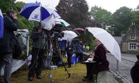 Journalists take shelter under umbrellas outside Balmoral.