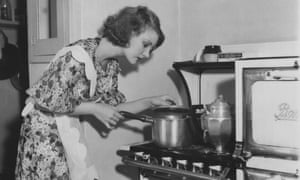 A vintage photo shows a lady bending over a pot to inspect the progress of her cooking.