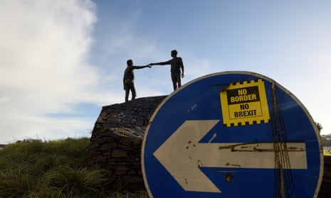 A ' No Border, No Brexit' sticker is seen on a road sign in front of the Peace statue entitled 'Hands Across the Divide' in Londonderry