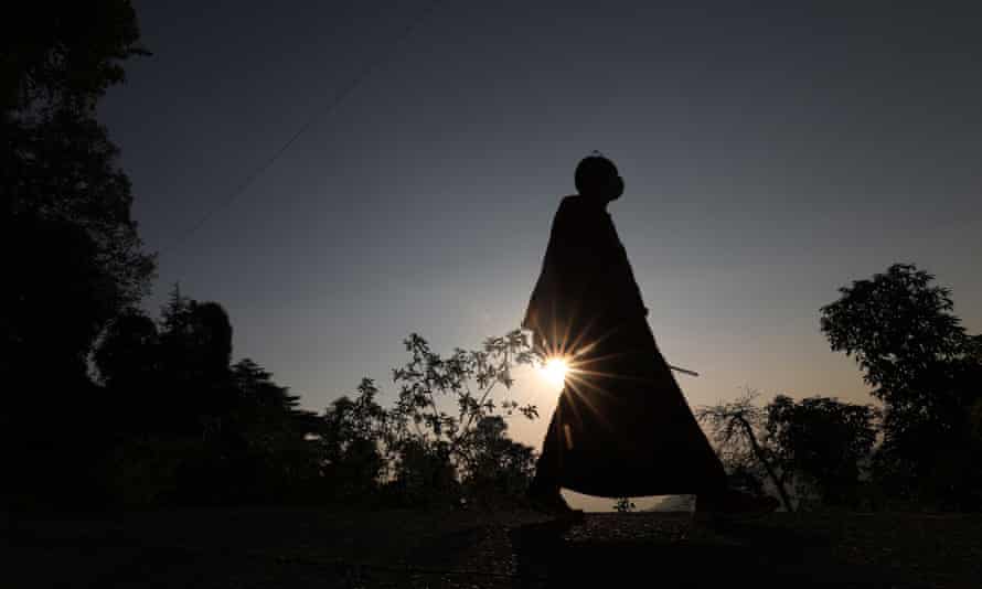 A Buddhist monk walks near the temple of Tsuglagkhang, popularly known as the Dalai Lama temple, at sunset in McLeod Ganj, Dharamsala