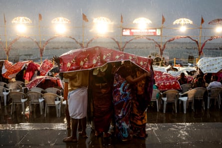 Tourists holding a red sheet over their heads in the rain