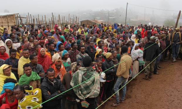 A crowd of hundreds of displaced people in Ethiopia wait for blankets and other aid