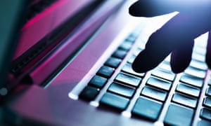 Close up of silhouetted male hand typing on laptop keyboard