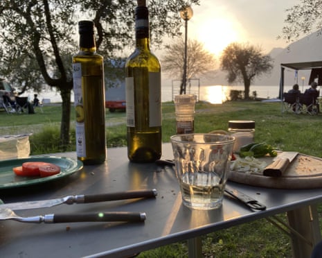 A camping table with a bottle of wine, plates, cutlery and leftover bits of food
