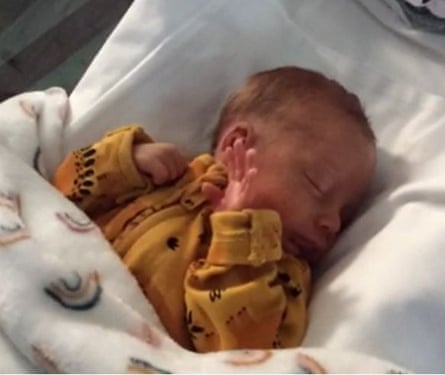 Baby in mustard yellow babygrow and white covers