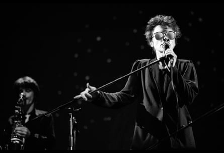 Laurie Anderson, wearing sunglasses, sings into a microphone on stage in Amsterdam, the Netherlands.