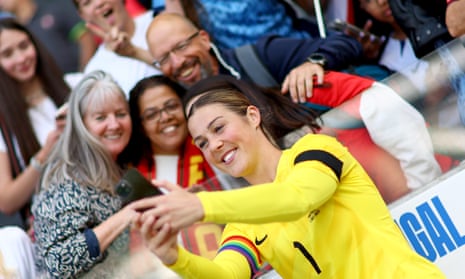Mary Earps in her yellow England No 1 jersey holds up a phone with both hands for a selfie as fans in the stand gather round to be in the picture