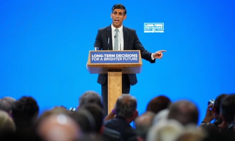 Rishi Sunak standing at a lectern in front of a blue backdrop