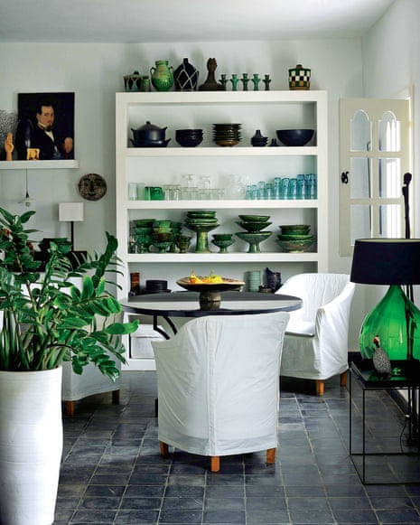 Glassware, ceramics and plants provide green accents in the sitting area by the kitchen
