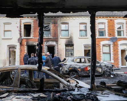 People inspect burnt-out cars and homes after Tuesday’s violence in east Belfast.