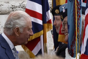 A close-up image of Charles chatting with two soldiers whose heads are partially obscured by flags