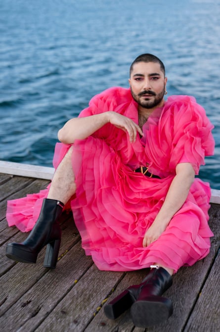 Deni Todorovič dans une robe à volants rose et des bottes noires à talons hauts assis sur une jetée