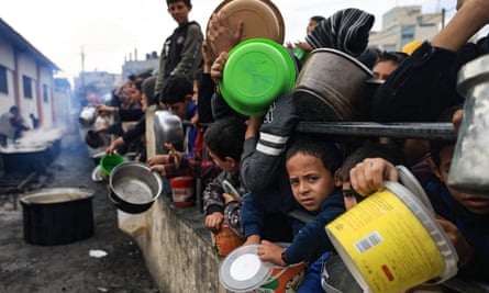 Children wait to collect food at a donation point in a refugee camp in Rafah, southern Gaza.