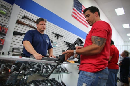 A man in a gun shop looking at a rifle