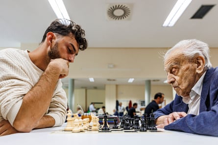 A young man and an older man play a game of chess.