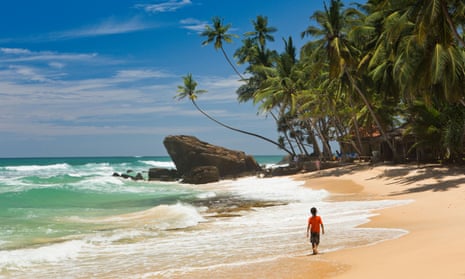 young boy alone walking on tropical Dalawella beach, Galle province, Sri Lanka.