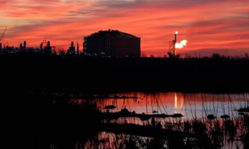 Oil facility beneath red sky at dusk