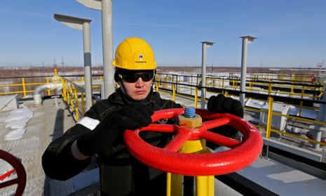 A worker turns a valve near oil storage tanks at a pumping station operated by Rosneft in Russia.