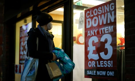 A shopper wearing a face covering looks in the window of a shop advertising a “Closing Down” sale sign in Walthamstow, north east London. 