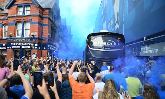 The people, freshly out of their pub, salute the arrival of their team in their bus at their club.