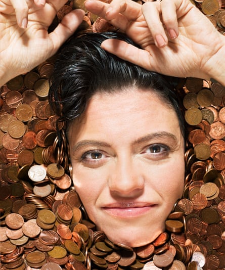 Jack Monroe shot from above in a bath filled with copper coins, with just her face and hands showing