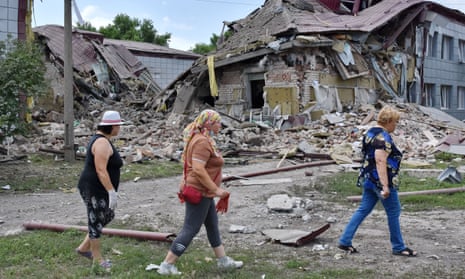 Local residents walk near a high school on Sunday after it was heavily damaged during Russian shelling in Komyshevakha, southern Ukraine