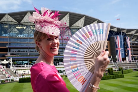 A racegoer holding a folding paper fan during day five of Royal Ascot