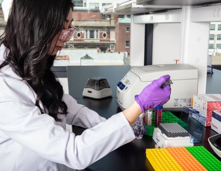 Gene technology entrepreneur Cathy Tie, in a white lab coat and purple gloves, with lab equipment