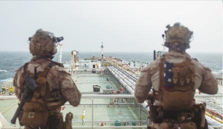 Two people in military uniform on board a large ship in the strait of Hormuz.