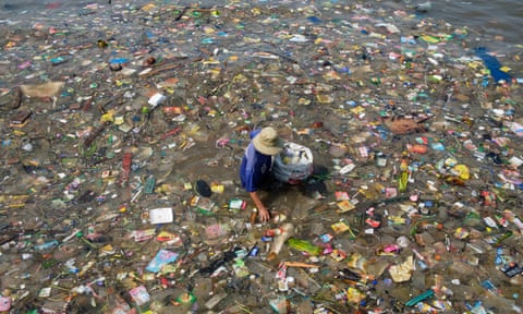 A fisherman picks though huge amounts of plastic waste washed up on the shore of a beach