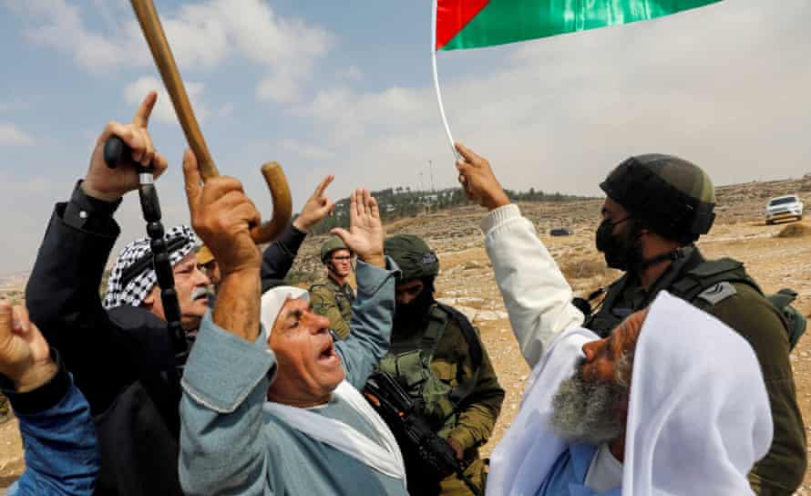 Manifestanti palestinesi fanno un gesto con le forze israeliane durante una protesta contro gli insediamenti israeliani a Masafar Yatta nell'ottobre 2021.