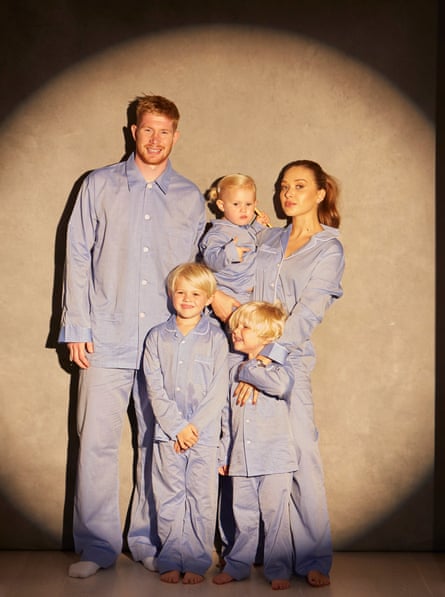 Manchester City footballer Kevin De Bruyne with his wife and three children, in matching pyjamas, against spotlight background, September 2022