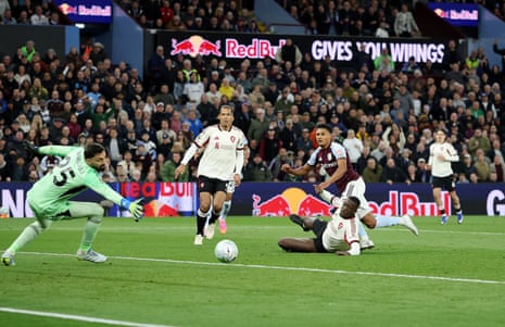 A Liverpool player slides on the ground as Aston Villa's Ollie Watkins shoots past him to score.