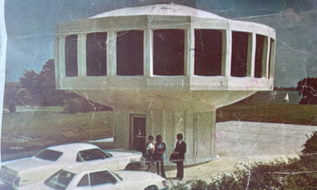 people talk under house shaped like a sideways wheel on a smaller, round base