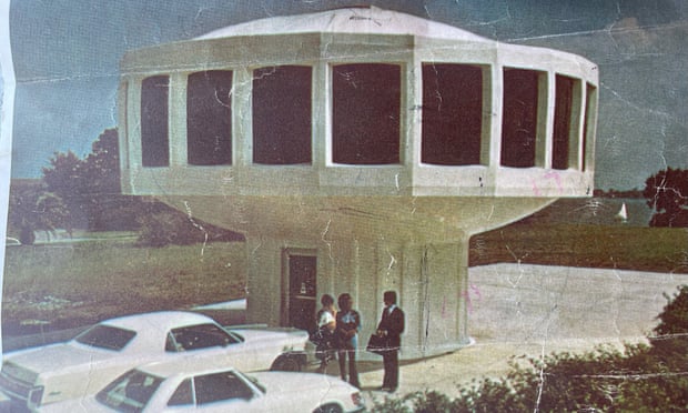 people talk under house shaped like a sideways wheel on a smaller, round base