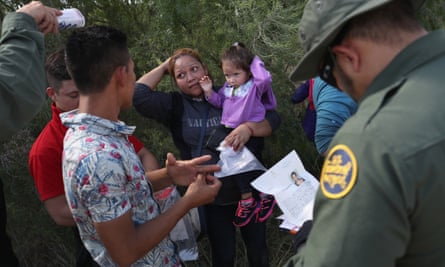 Border patrol officers talk with a group of Central American asylum seekers before taking them into custody on 12 June 2018 near McAllen, Texas.